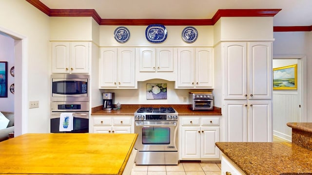 kitchen featuring crown molding, appliances with stainless steel finishes, light tile patterned flooring, and white cabinets