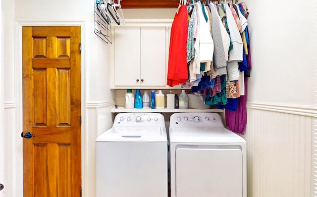 laundry room with a wainscoted wall, cabinet space, and washing machine and clothes dryer