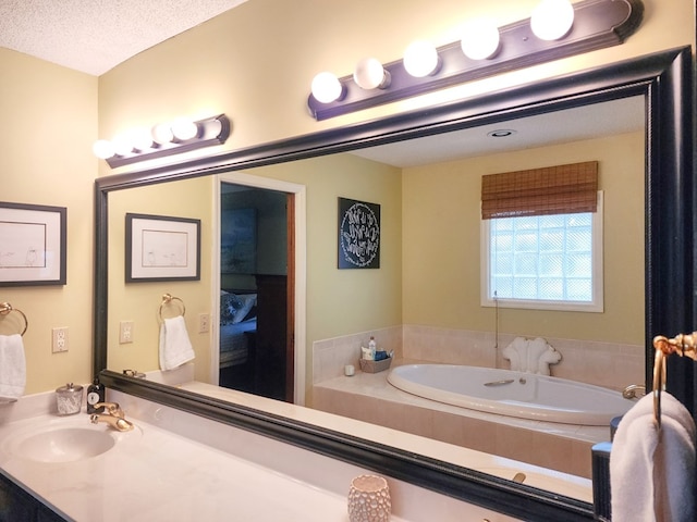 full bathroom featuring a textured ceiling, a garden tub, and vanity