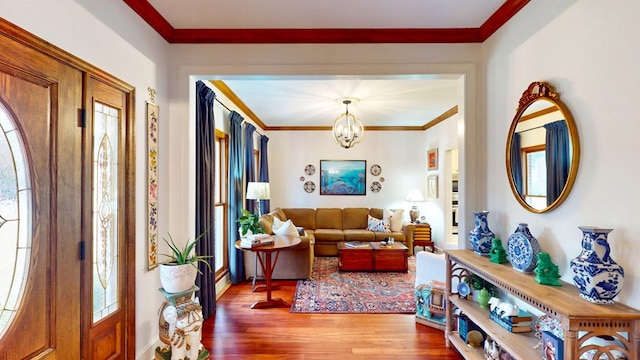 entrance foyer featuring ornamental molding, a chandelier, and wood finished floors