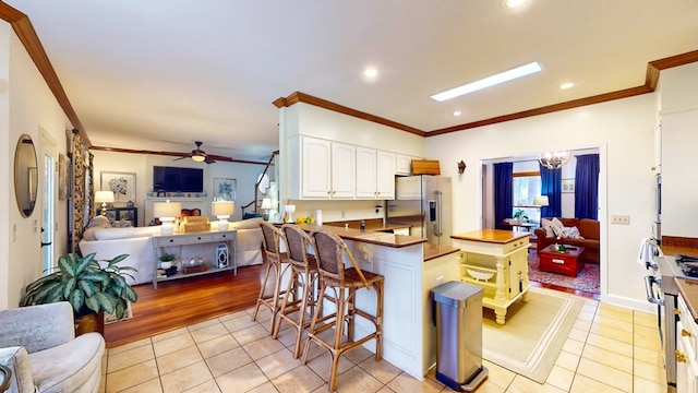 kitchen with white cabinets, light tile patterned floors, stainless steel appliances, and open floor plan