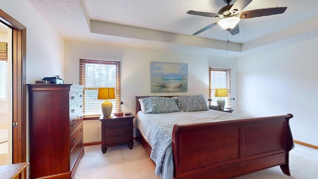 bedroom featuring a textured ceiling, a tray ceiling, and multiple windows