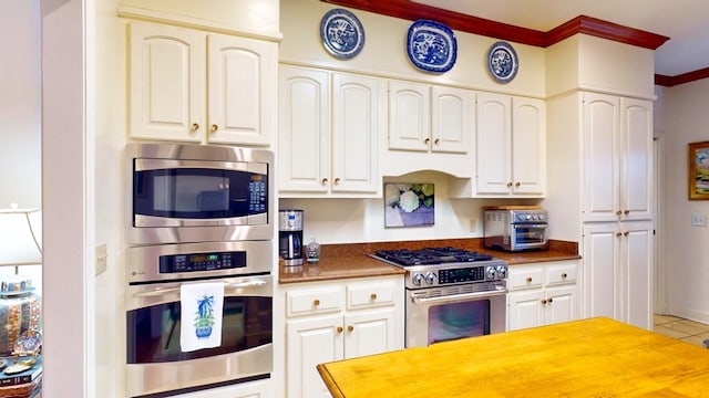 kitchen featuring white cabinets, appliances with stainless steel finishes, wooden counters, and crown molding