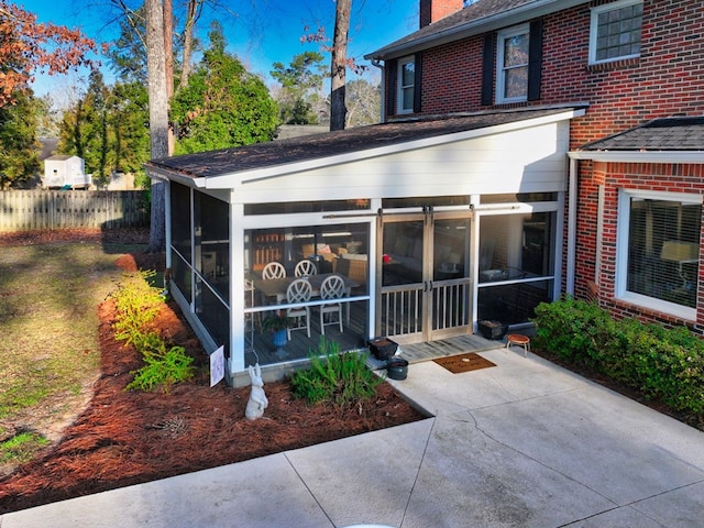 exterior space featuring brick siding, a chimney, and a sunroom