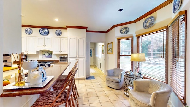 kitchen with light tile patterned floors, plenty of natural light, white cabinetry, and crown molding