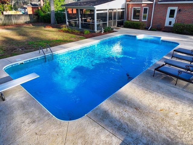 view of swimming pool featuring fence, a sunroom, a diving board, a lawn, and a fenced in pool