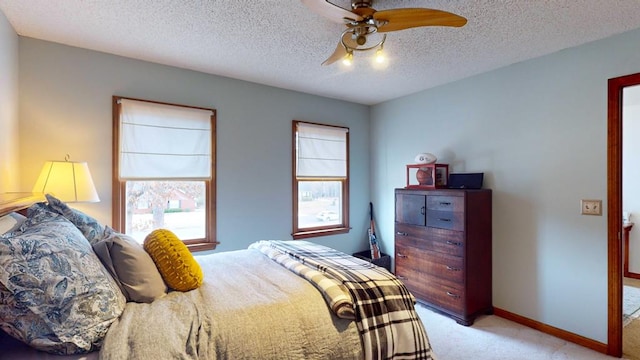 bedroom with baseboards, ceiling fan, a textured ceiling, and light colored carpet