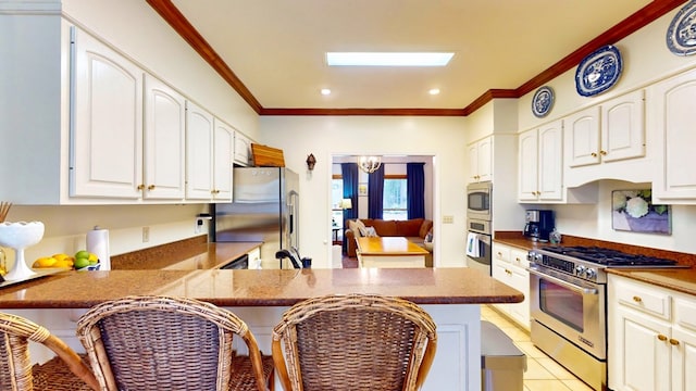 kitchen featuring a peninsula, white cabinetry, appliances with stainless steel finishes, and ornamental molding