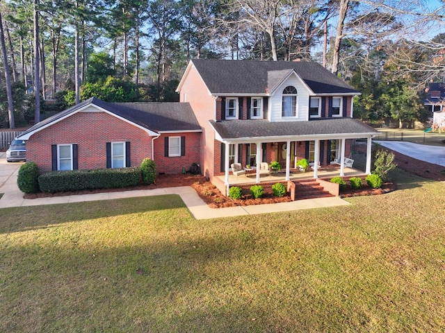 view of front facade featuring a porch, a front yard, and brick siding