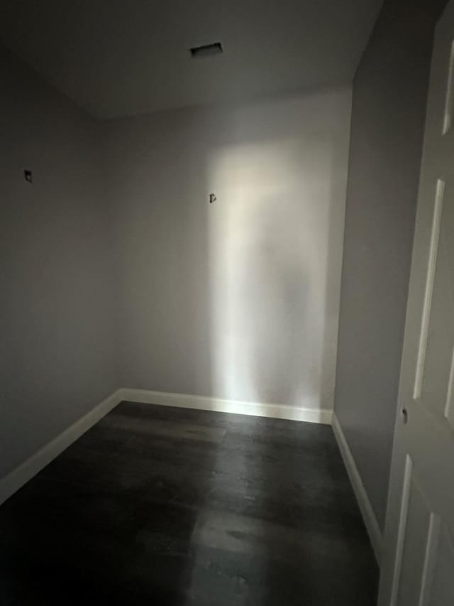 spare room featuring dark wood-style floors and baseboards