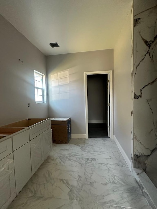 bathroom featuring marble finish floor and baseboards