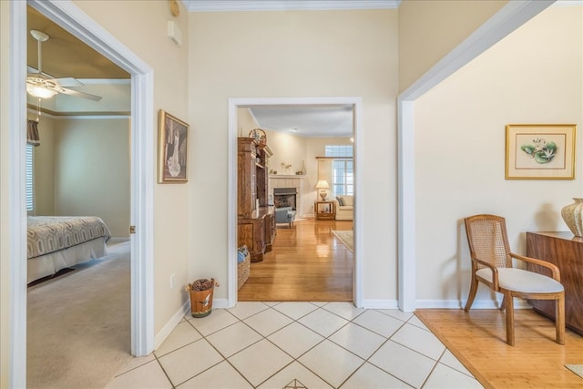 hall with crown molding, baseboards, and light tile patterned floors