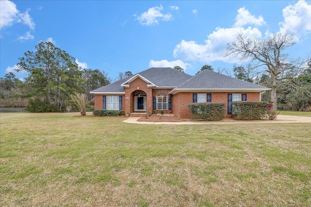 ranch-style house featuring brick siding, a front lawn, and a shingled roof