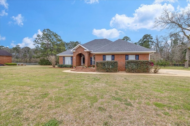 ranch-style house featuring brick siding, a front lawn, and roof with shingles