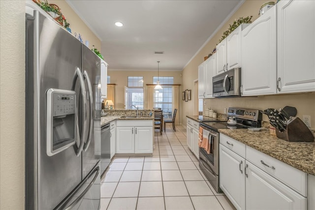 kitchen with light tile patterned floors, stainless steel appliances, ornamental molding, white cabinets, and a sink