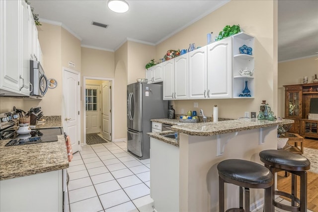 kitchen with visible vents, white cabinets, appliances with stainless steel finishes, light stone counters, and a peninsula