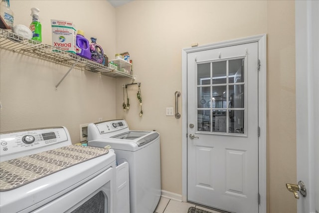 washroom with laundry area, washer and clothes dryer, baseboards, and light tile patterned floors