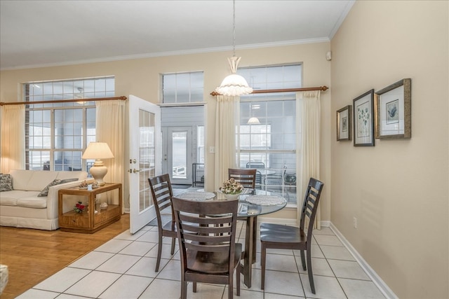 dining space with light tile patterned floors, baseboards, crown molding, and french doors