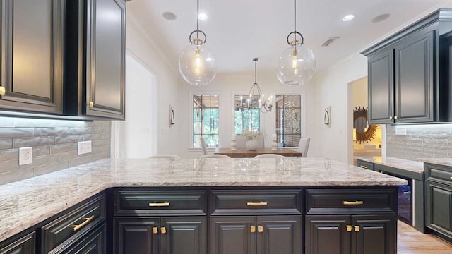 7827 Metcalf Rd, Thomasville, GA 31792 - kitchen with a peninsula, ornamental molding, backsplash, a chandelier, and light stone countertops