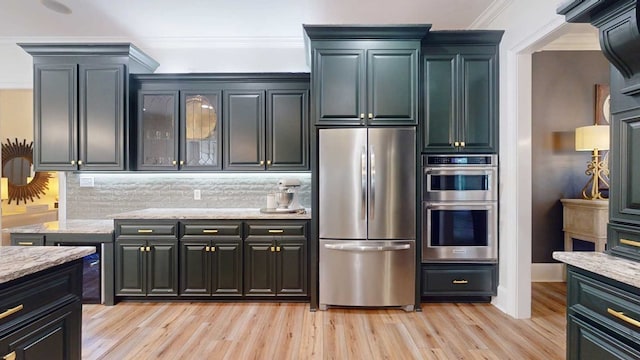 7827 Metcalf Rd, Thomasville, GA 31792 - kitchen featuring appliances with stainless steel finishes, ornamental molding, tasteful backsplash, light wood-style floors, and light stone counters