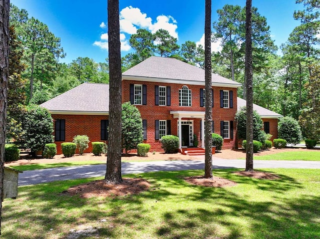 7827 Metcalf Rd, Thomasville, GA 31792 - colonial-style house featuring a front lawn, brick siding, and curved driveway
