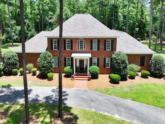 7827 Metcalf Rd, Thomasville, GA 31792 - colonial home featuring a chimney, brick siding, and roof with shingles