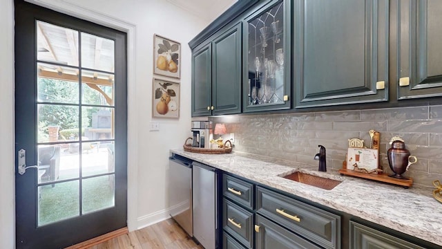 7827 Metcalf Rd, Thomasville, GA 31792 - kitchen featuring decorative backsplash, light stone countertops, light wood-type flooring, and glass insert cabinets