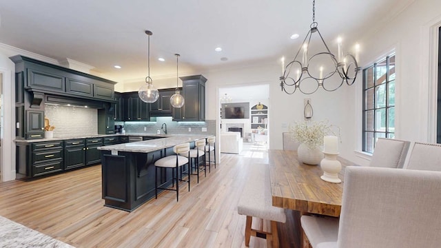 7827 Metcalf Rd, Thomasville, GA 31792 - kitchen featuring crown molding, a breakfast bar area, tasteful backsplash, light wood-style flooring, and a chandelier