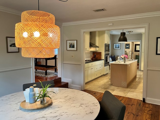 dining room featuring light wood-style floors, visible vents, a chandelier, and ornamental molding