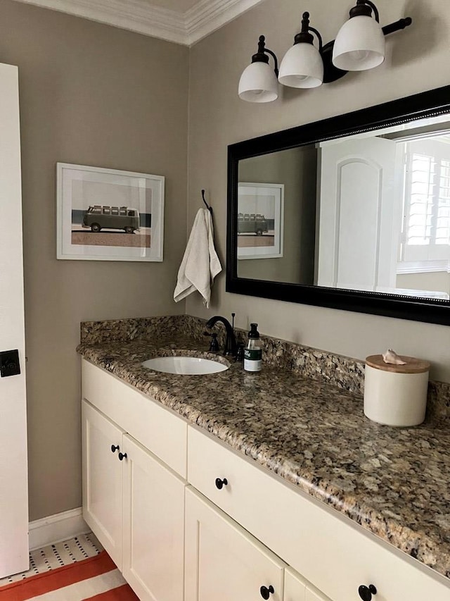 bathroom featuring baseboards, ornamental molding, and vanity