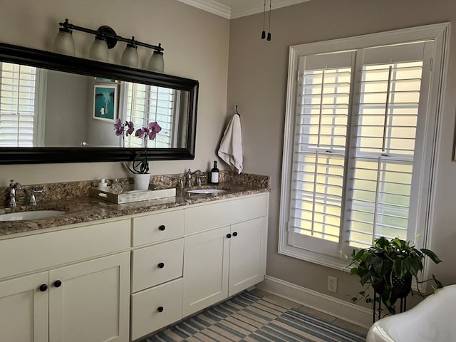 bathroom featuring a soaking tub, crown molding, baseboards, and a sink