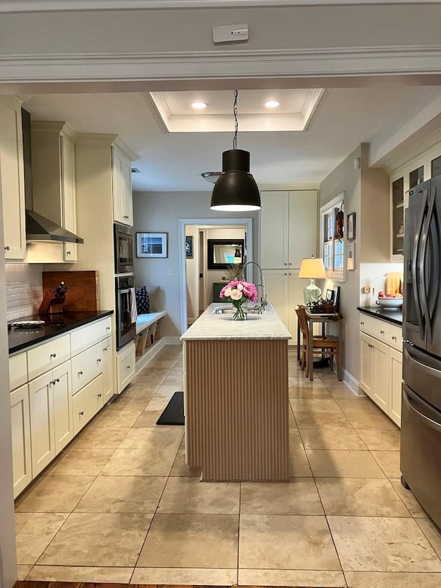 kitchen featuring a tray ceiling, wall chimney exhaust hood, fridge with ice dispenser, and a sink