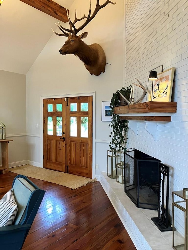 entryway with beamed ceiling, a brick fireplace, high vaulted ceiling, and hardwood / wood-style flooring