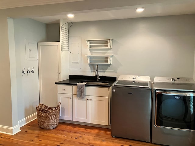 laundry area featuring washer and dryer, cabinet space, light wood-type flooring, and a sink