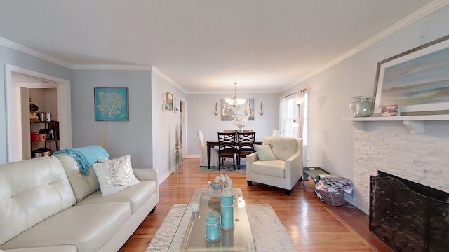 living room with crown molding, a fireplace, a chandelier, and hardwood / wood-style floors