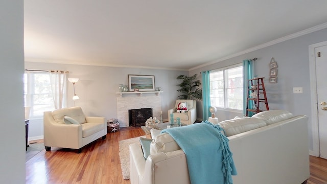 living room featuring crown molding, hardwood / wood-style floors, and a stone fireplace