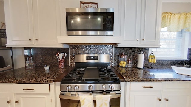 kitchen with white cabinetry, tasteful backsplash, dark stone countertops, and appliances with stainless steel finishes