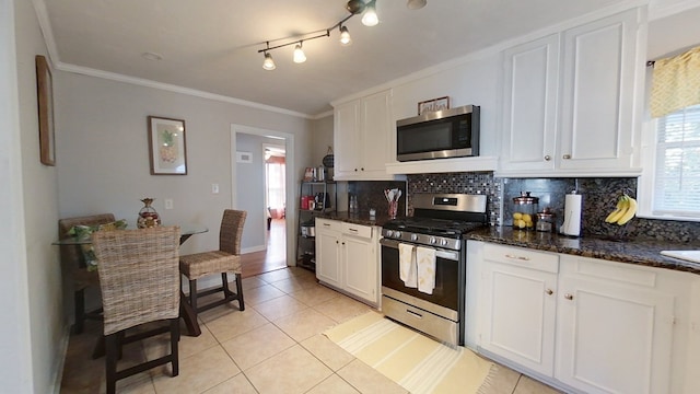 kitchen featuring light tile patterned flooring, appliances with stainless steel finishes, white cabinets, backsplash, and dark stone counters