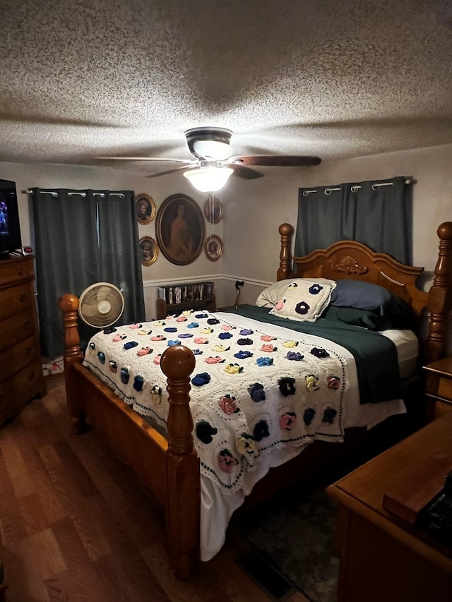 bedroom featuring dark hardwood / wood-style flooring, ceiling fan, and a textured ceiling