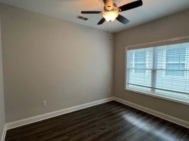 empty room with dark hardwood / wood-style floors and ceiling fan