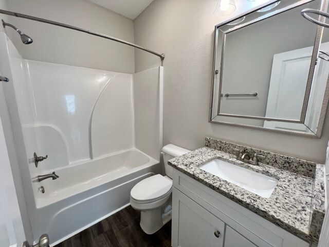 full bathroom featuring shower / bathing tub combination, hardwood / wood-style floors, vanity, and toilet