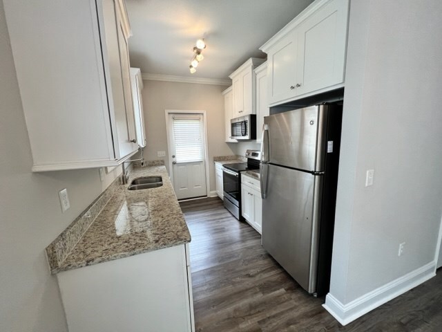 kitchen featuring stainless steel appliances, light stone countertops, sink, and white cabinets