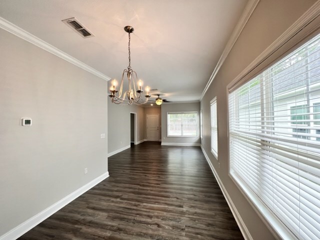 unfurnished dining area with dark hardwood / wood-style flooring, ornamental molding, and a chandelier