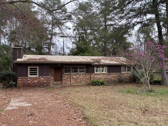 ranch-style house featuring brick siding, board and batten siding, and a chimney