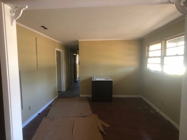 hall with baseboards, visible vents, crown molding, and wood finished floors