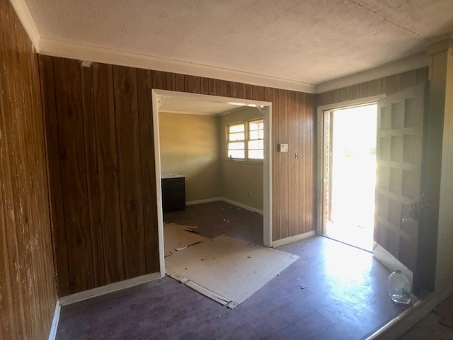 foyer featuring ornamental molding, wood walls, and baseboards