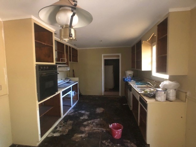 kitchen with ornamental molding, open shelves, a sink, and oven