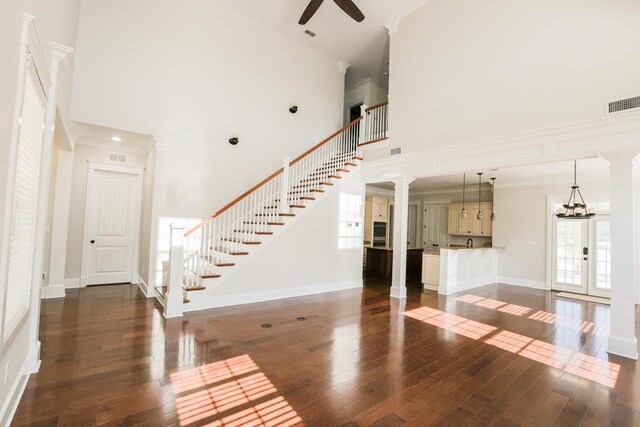 interior space featuring dark hardwood / wood-style flooring, decorative columns, and a high ceiling