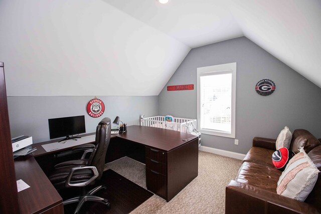 carpeted office space featuring vaulted ceiling