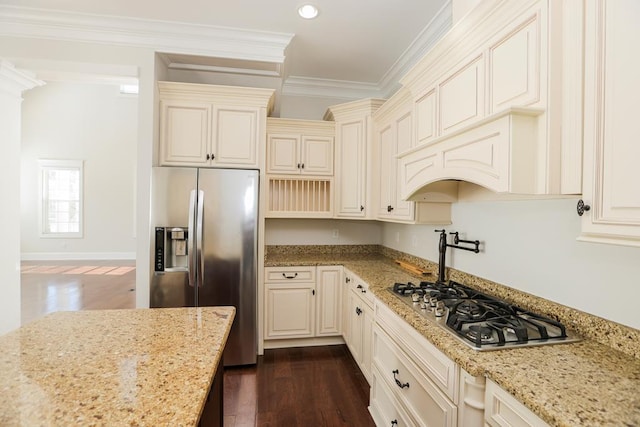 kitchen with light stone counters, ornamental molding, appliances with stainless steel finishes, and cream cabinetry